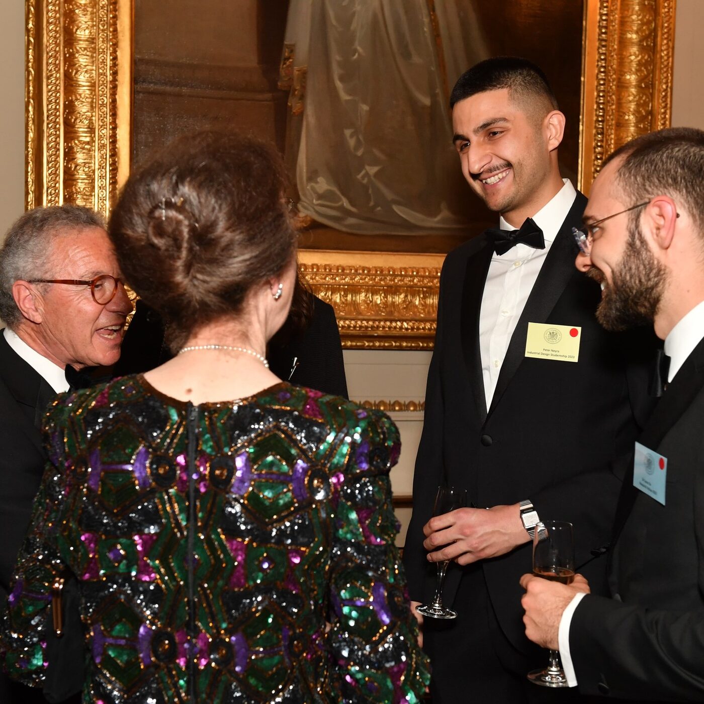Peter in black tie laughs mid-conversation at the 1851 Presidential Dinner, champagne in hand