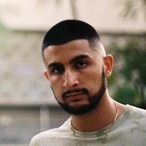 Headshot of a young man with a fade haircut and beard