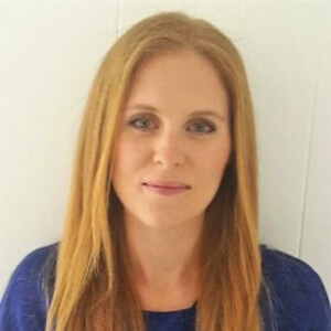 Headshot of a woman with long strawberry-blonde hair in a blue top