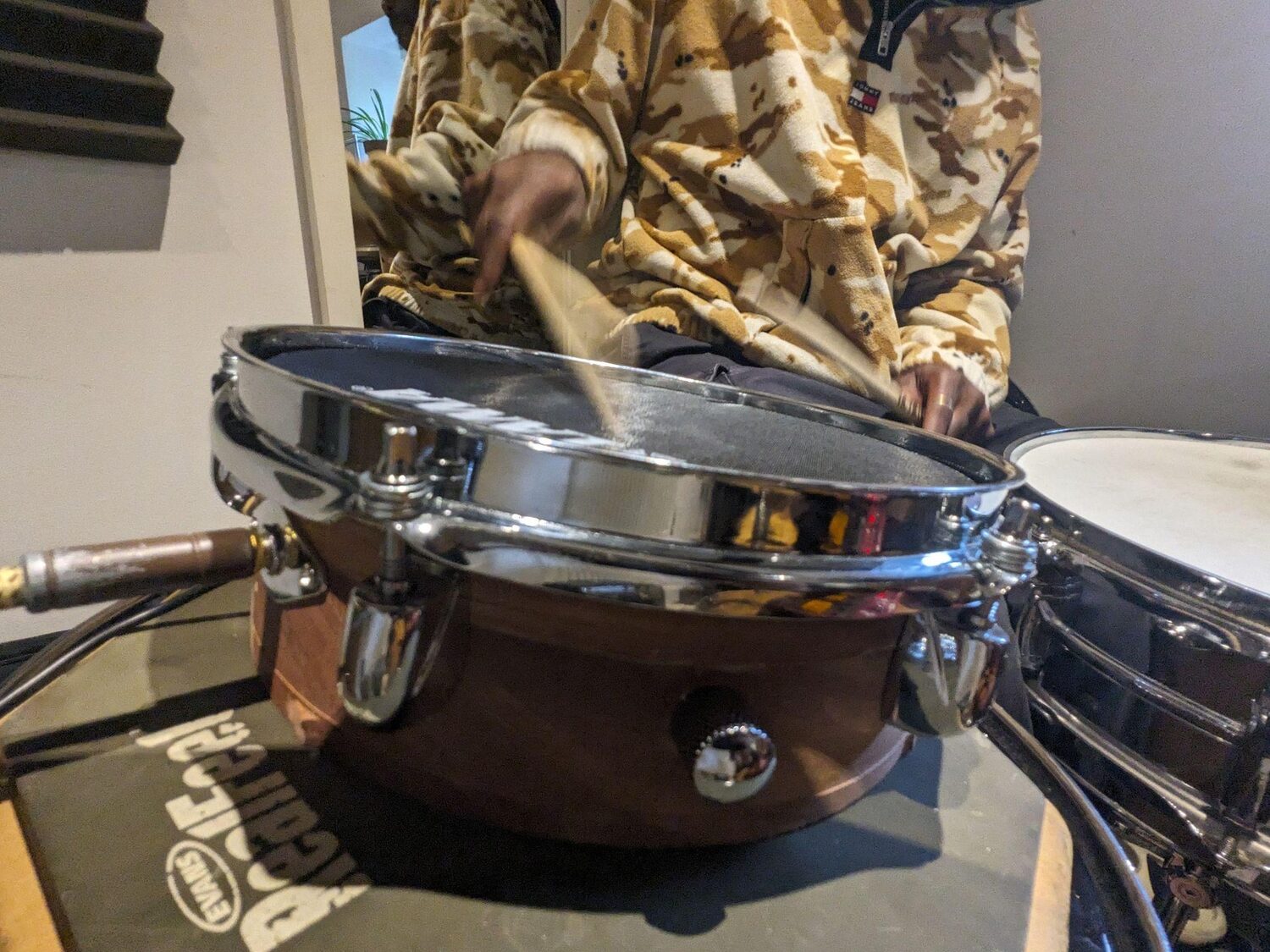 Drummer Ayo Salawu's hands testing the mesh-head wooden electric drum with sticks