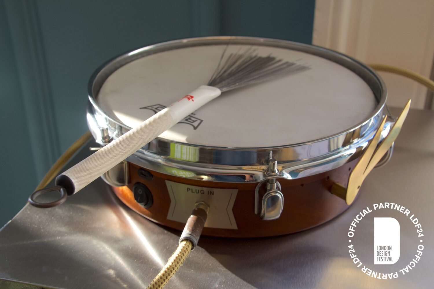 Finished wooden electric drum with wire brush in warm light at London Design Festival 2024