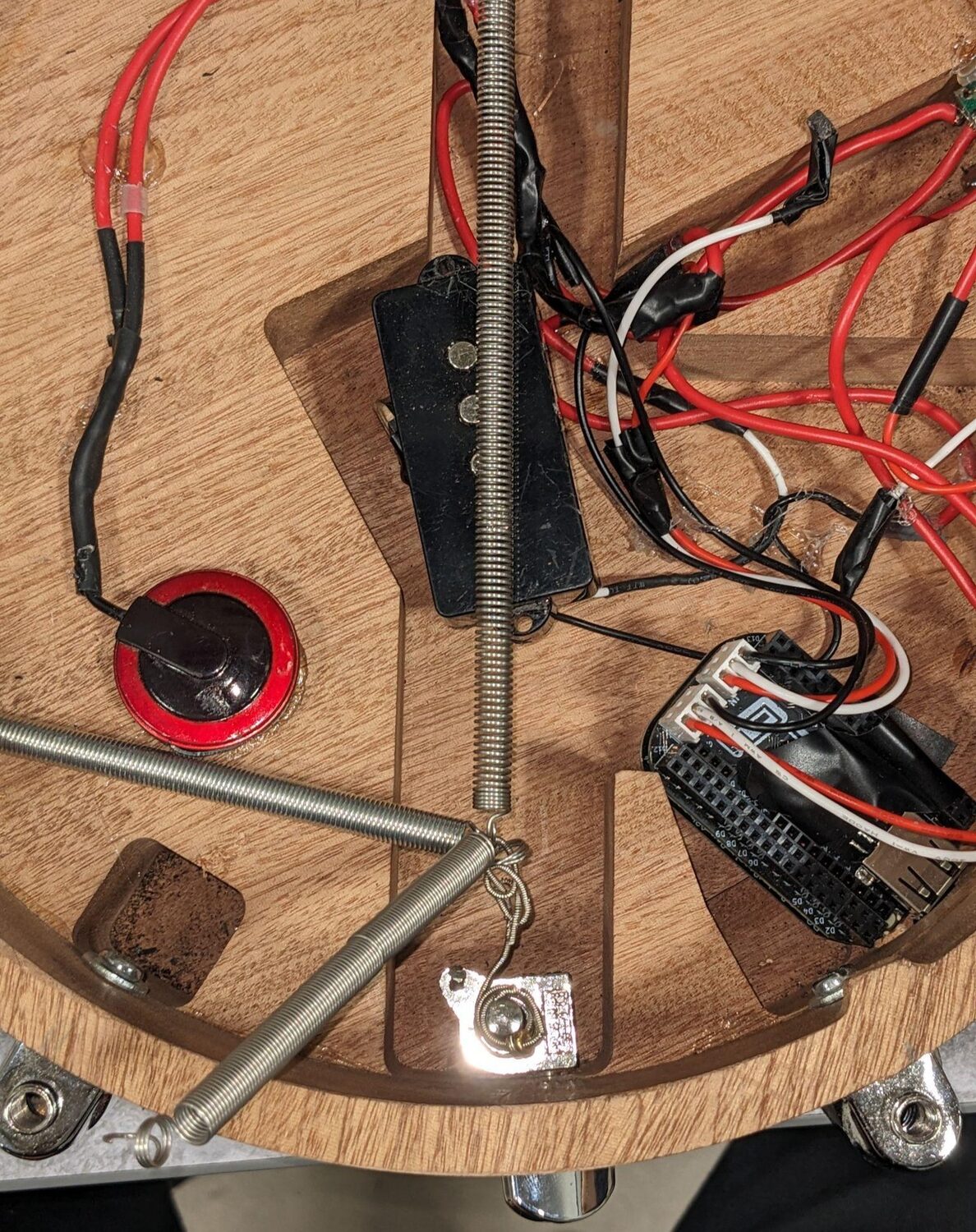 Inside the drum shell: tension spring, piezo disc, pickup and hand wiring on wooden bracing