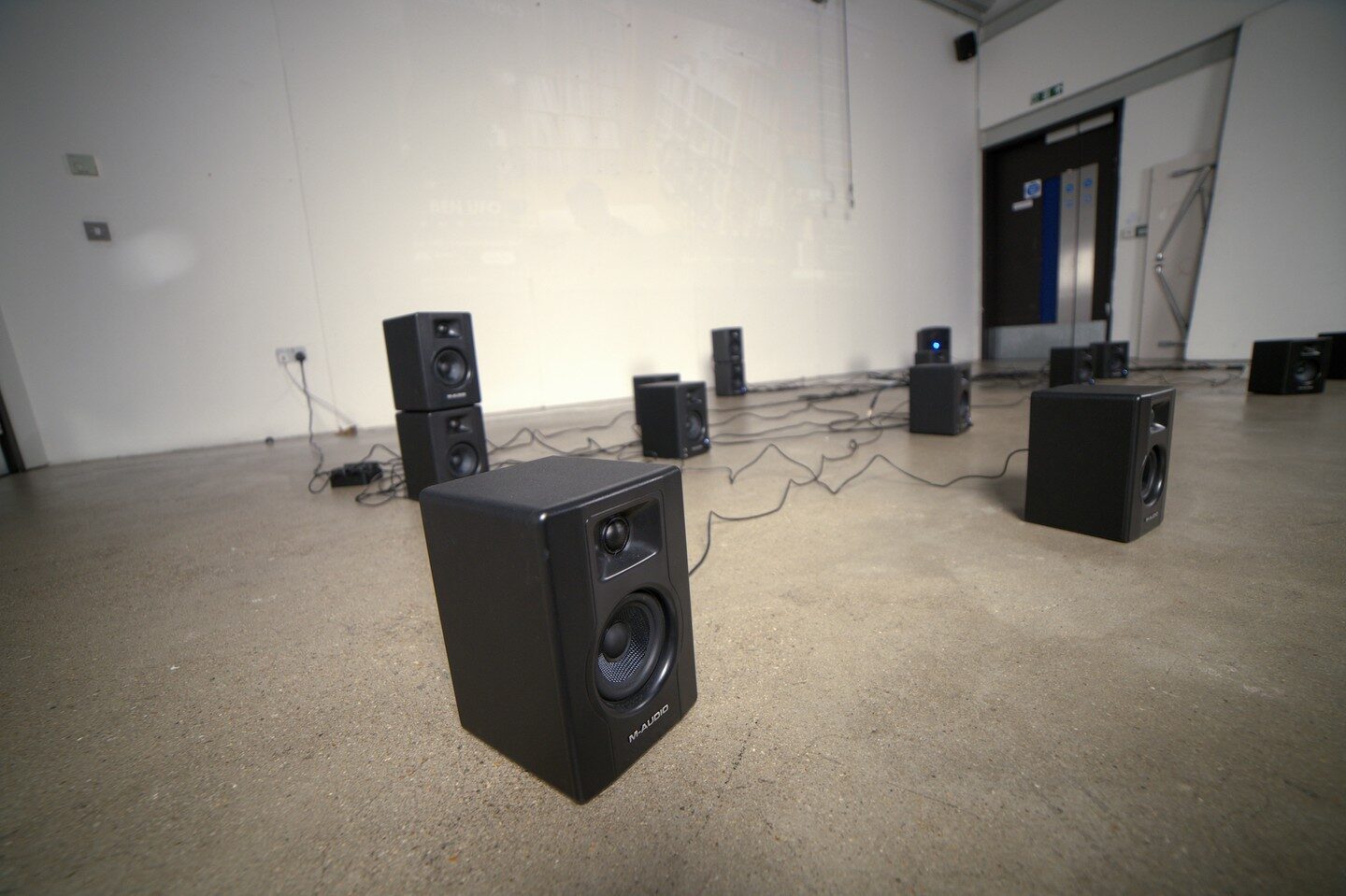 Close-up of an M-Audio floor monitor with the speaker web receding behind