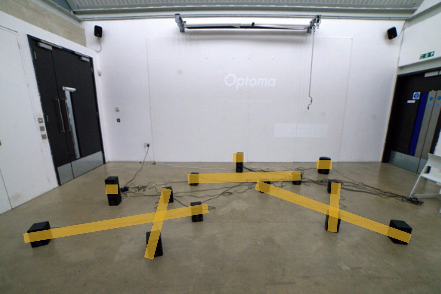 Yellow layout bars overlaid on a photo of the speaker arrangement in the daylit studio