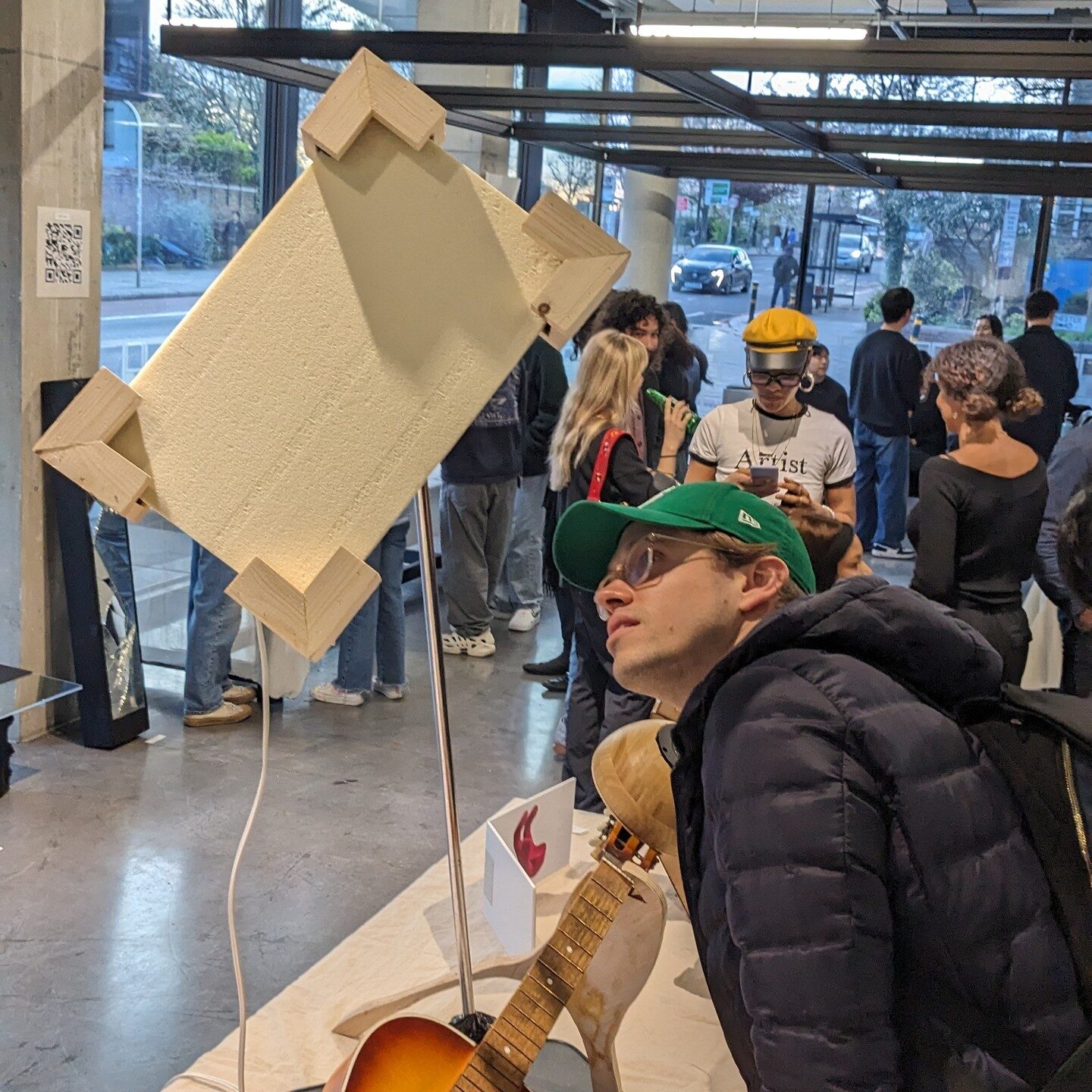 Visitor leaning in to the speakers as a crowd fills the gallery