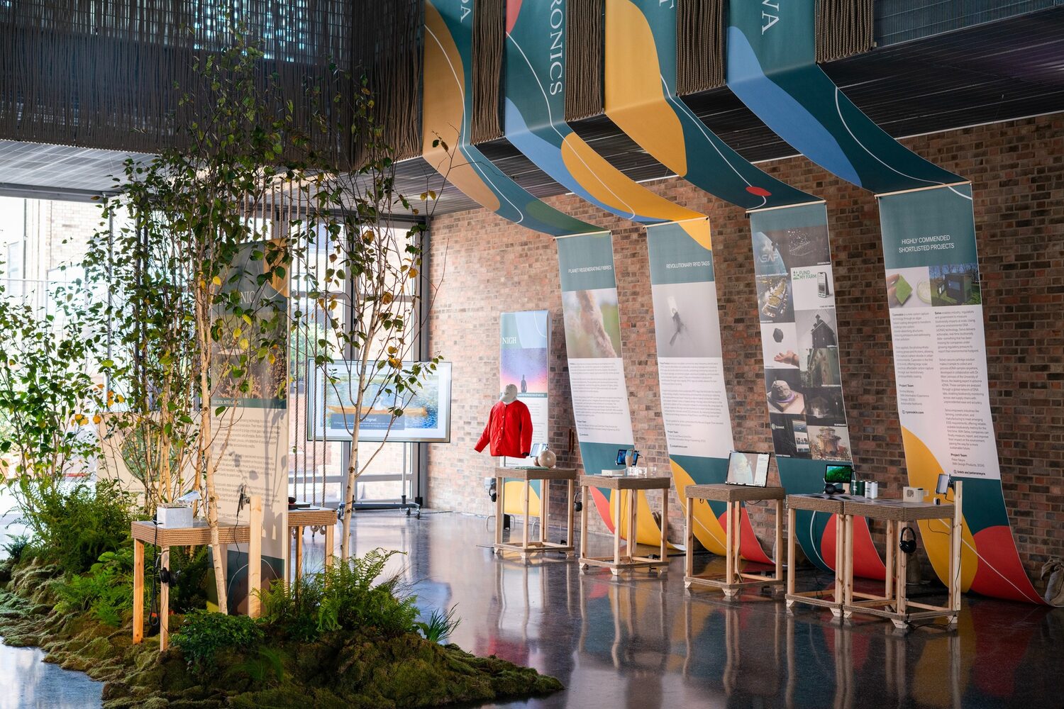 Wide view of the Terra Carta Design Lab exhibition hall with banners and plinths